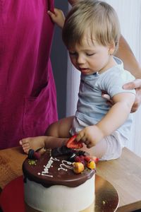 High angle view of mother and cute boy eating cake at his birthday