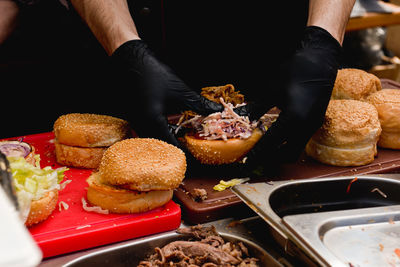 Midsection of vendor preparing hamburgers on table at market