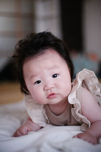 Portrait of cute baby girl on bed at home