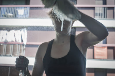 Midsection of man holding glass while standing by window