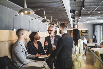 Senior businessman discussing with colleagues during coffee break in office