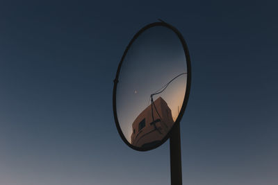 Low angle view of mirror against blue sky