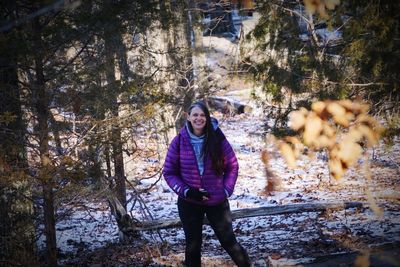 Portrait of young woman standing in forest during winter