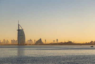 View of buildings by river against sky during sunset