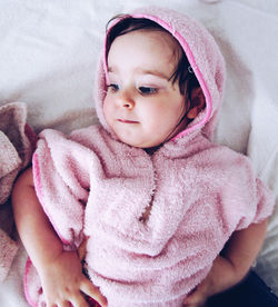 Portrait of cute baby girl lying on bed