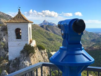 Binoculars and bell tower against sky