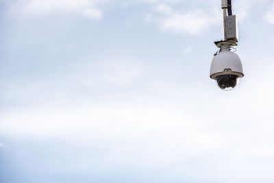 Low angle view of electric lamp hanging against sky