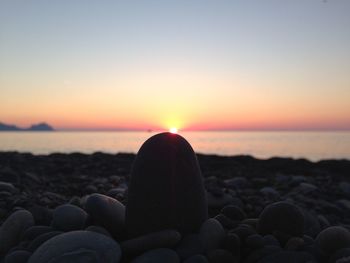 Close-up of pebbles at beach against clear sky during sunset