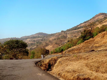 Road by mountains against clear blue sky