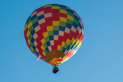 Low angle view of colorful hot air balloon flying against clear blue sky