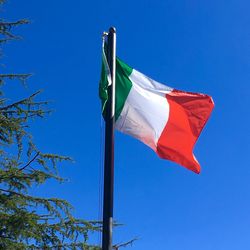 Low angle view of flag against blue sky