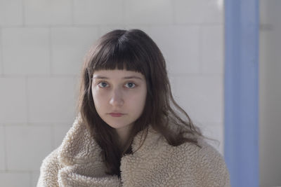 Portrait of young woman against wall