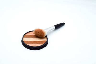 Close-up of make-up with brush over white background