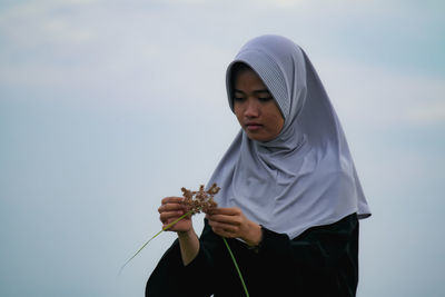 Portrait of young woman standing against sky