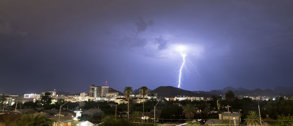 Lightning over illuminated buildings in city at night