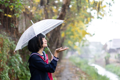 Woman with umbrella standing on rainy day