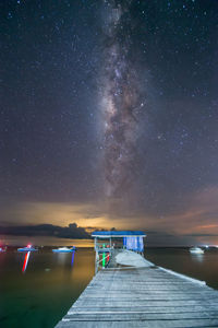 Pier over sea against sky at night