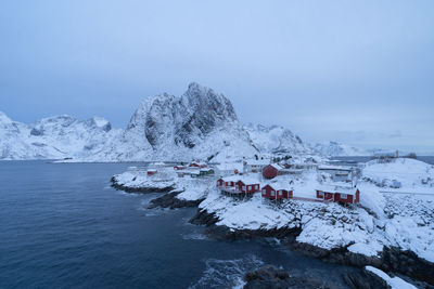 Scenic view of sea by snowcapped mountain against sky