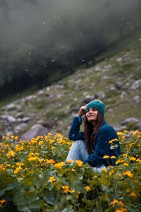 Low angle view of young woman sitting amidst flowers