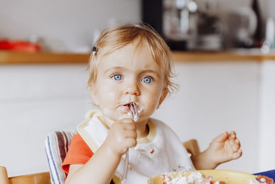 Portrait of cute baby girl eating at home