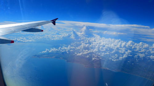 Airplane flying over snowcapped mountains against blue sky