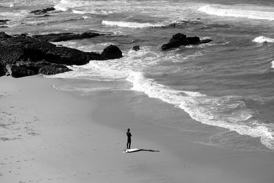 High angle view of surfer standing at beach