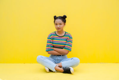 Portrait of boy sitting against yellow background