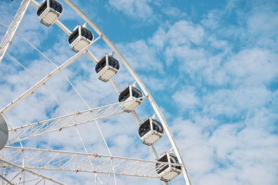 Ferris wheel rotates against background of blue cloudy sky. amusement park attraction