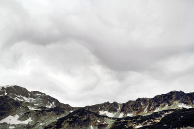 Rocky mountains against cloudy sky during winter