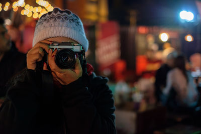 Woman photographing in illuminated city at night