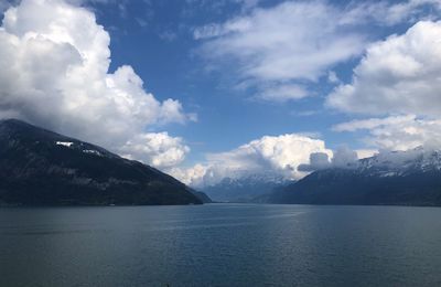 Scenic view of sea by mountains against sky