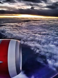 Close-up of airplane flying over sea against sky during sunset