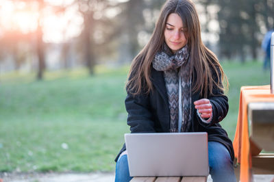 Young woman using laptop at park