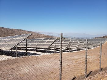 Fence on landscape against clear blue sky