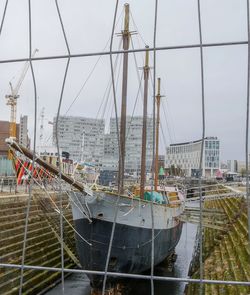 Sailboats moored at harbor against sky