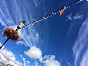 Low angle view of bunting flags hanging from gas light against sky
