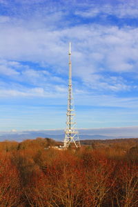 Low angle view of communications tower on field against sky