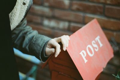 Cropped image of person touching public mailbox