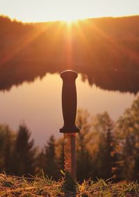 Silhouette cross on landscape against sky during sunset