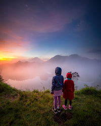 Rear view of people on mountain against sky during sunset