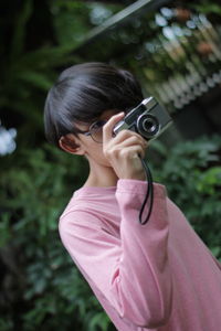 Midsection of woman photographing with pink camera