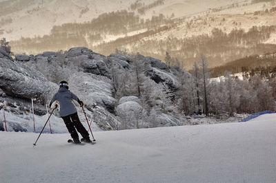 Rear view of person skiing on snow covered field