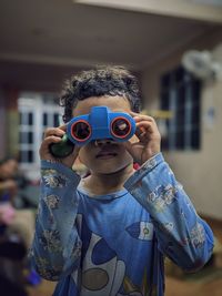 Young boy holding a toy binocular.
