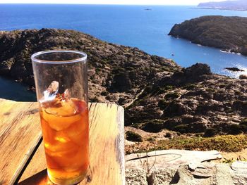 Close-up of drink on table by sea against sky