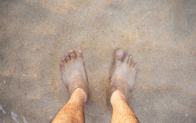 Low section of man standing in water