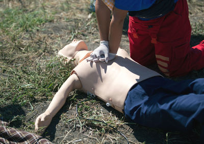 Midsection of woman examining cpr dummy on field