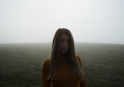 Portrait of young woman standing against sea