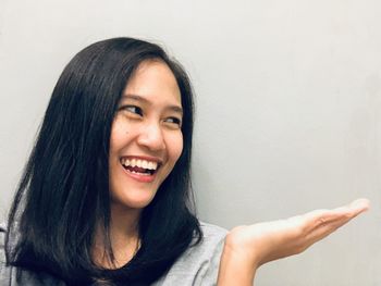 Portrait of smiling young woman against wall