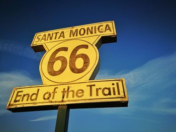 Low angle view of road sign against blue sky