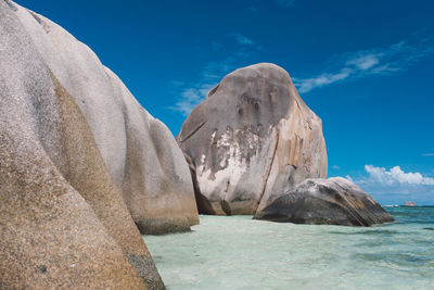 Rock formations by sea against blue sky